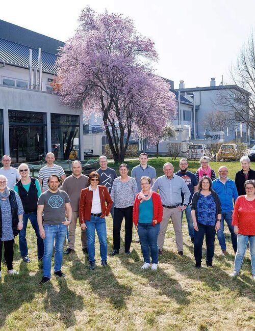 ITVP employees stand on a grassy area in front of the company building.